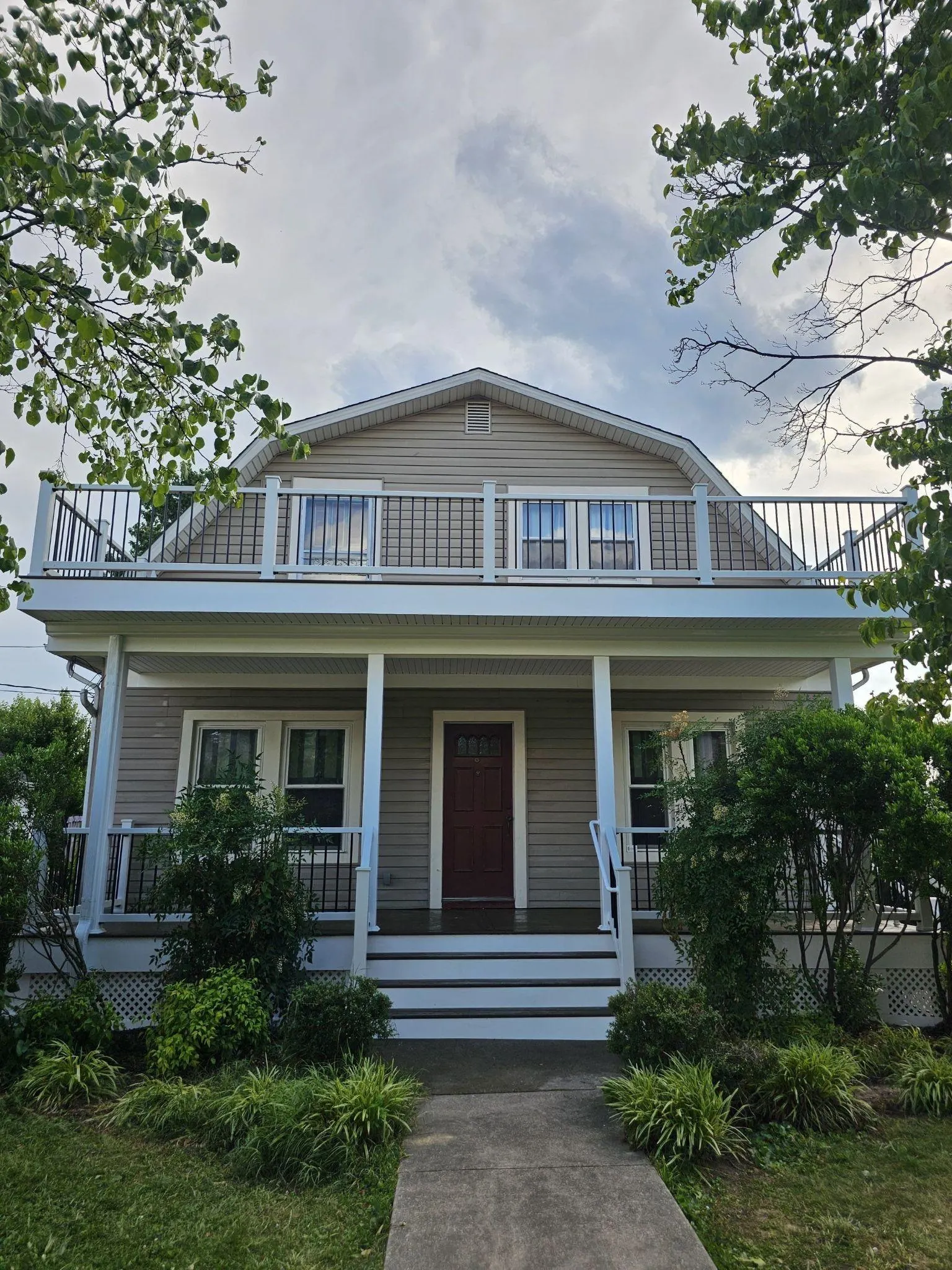 Rebuilt Ellicott City front porch with a second-story Trex deck, white columns, and black railings.