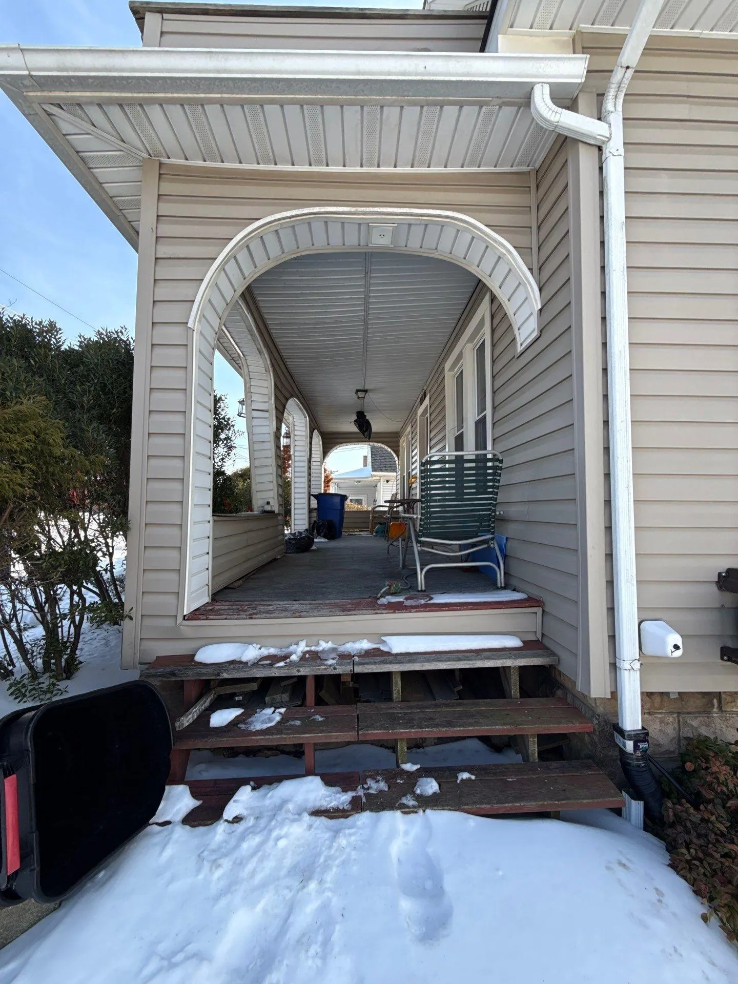 Deteriorated porch steps and vinyl-wrapped columns before reconstruction