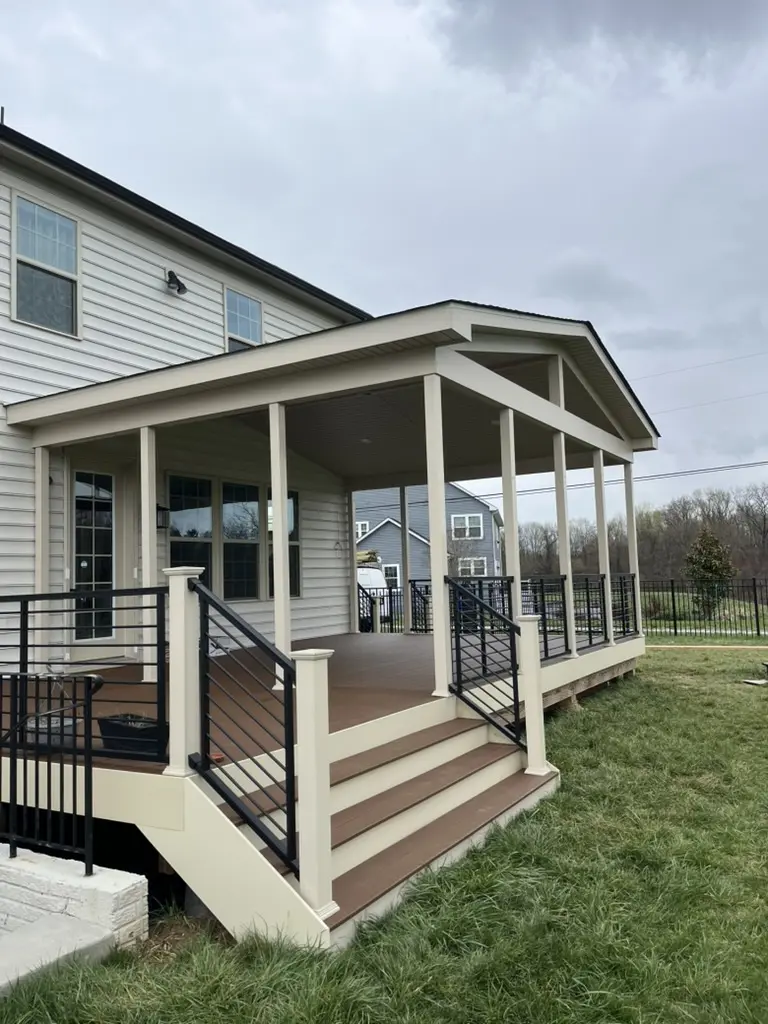 Covered porch with composite decking and black metal railing.