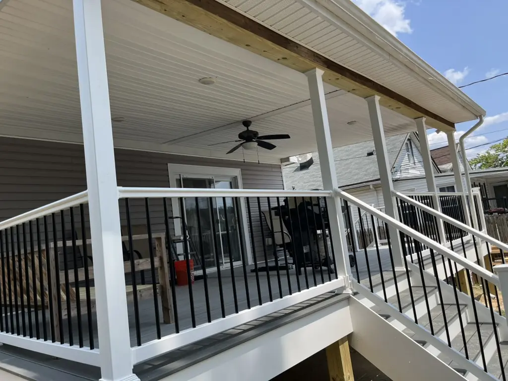 Covered porch with ceiling fan and white railing.