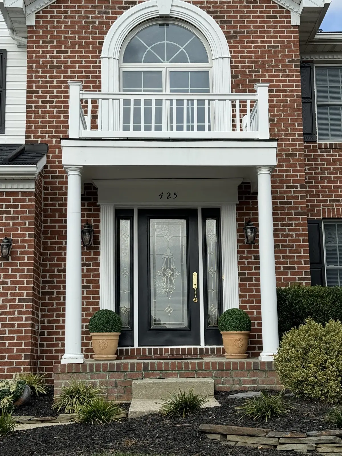 Custom columned front-entry portico on a brick home by Classic Remodeling.