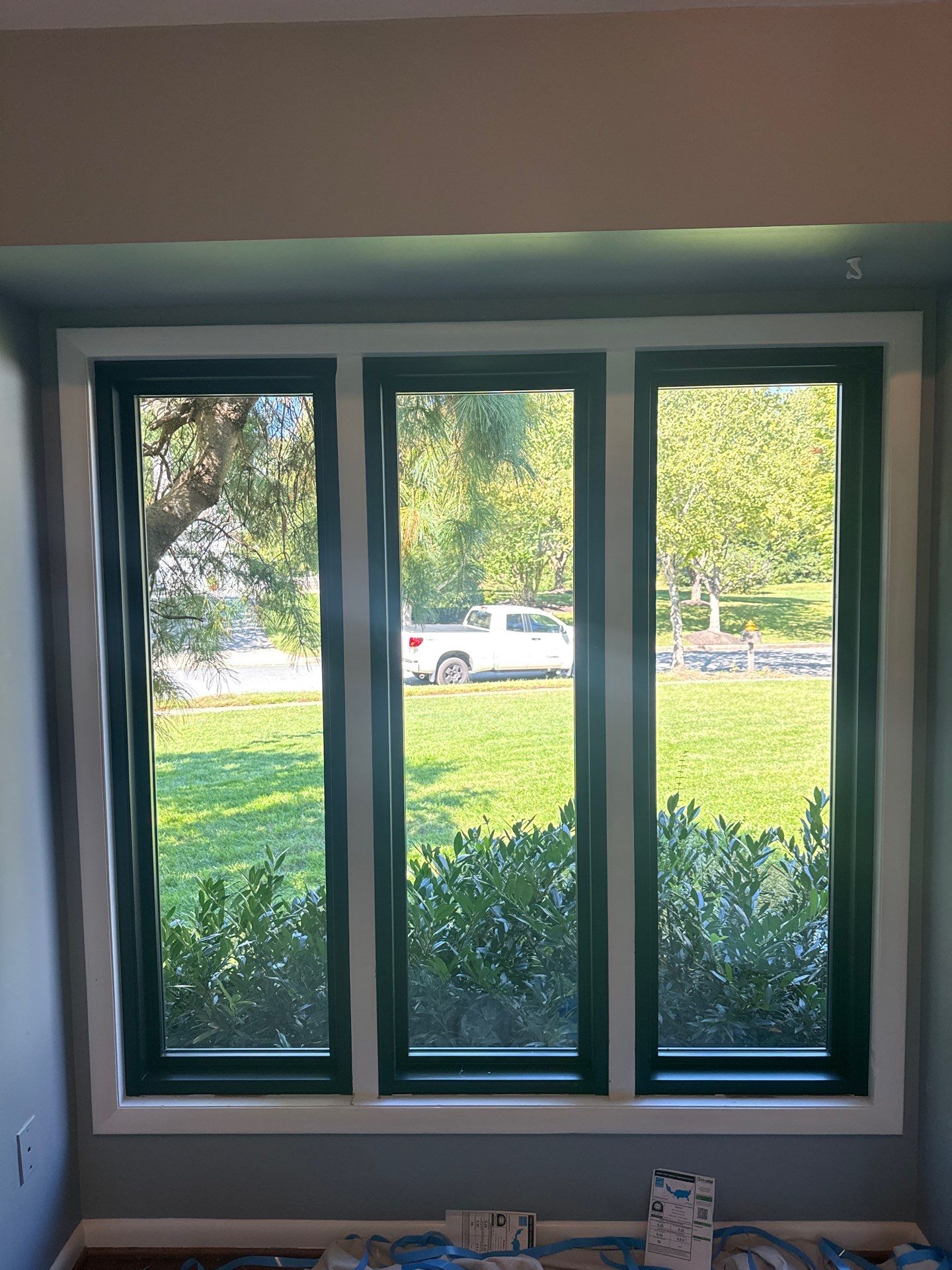 Front three-window opening before and after replacement with black casement windows in Ellicott City, Maryland